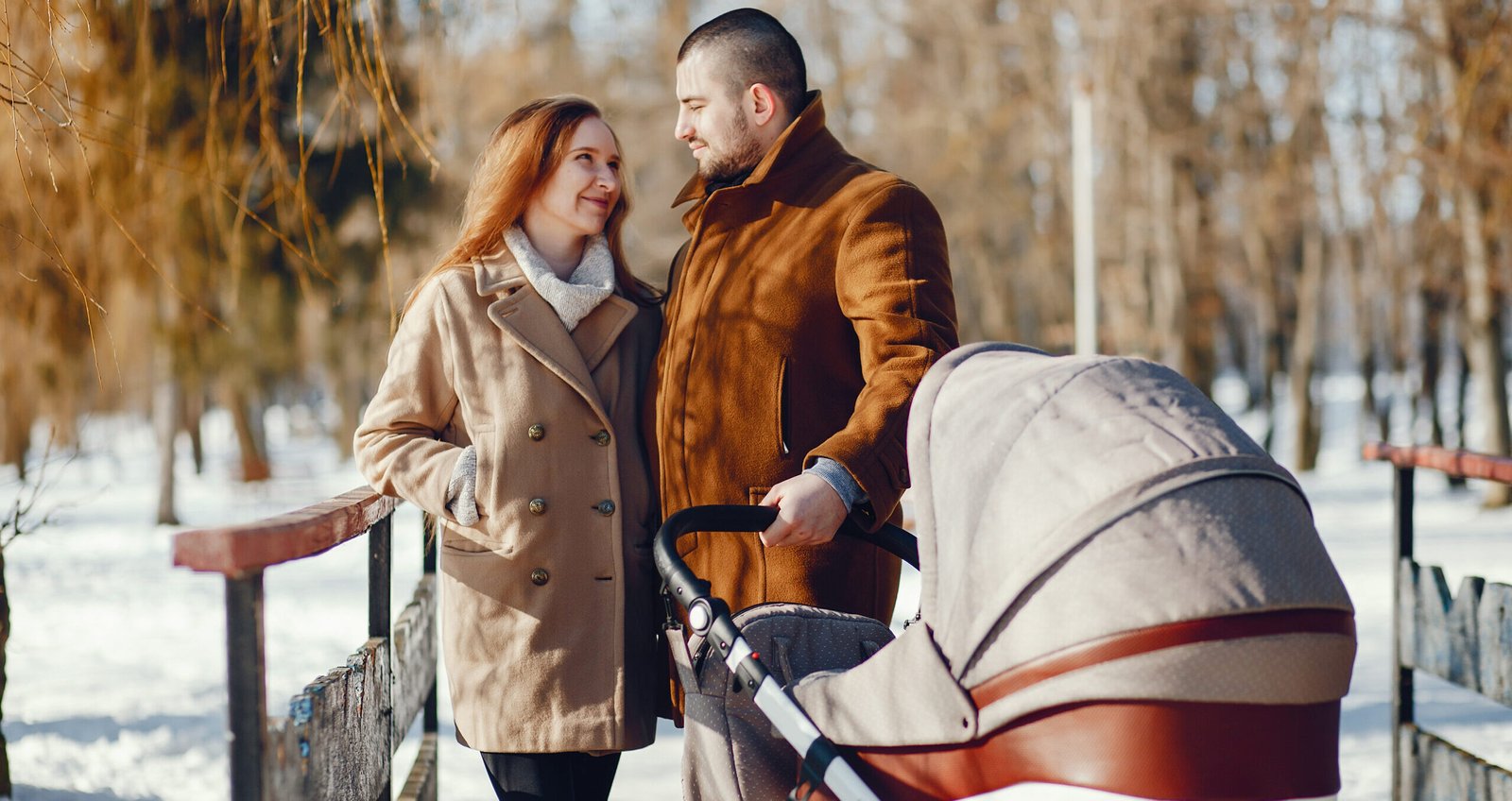 Elegant family in a winter forest. Mother with carriage. Man in a brown coat